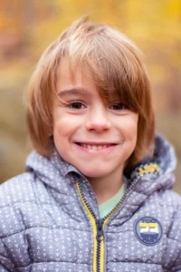 lächelnder Junge in Jacke, bei einem Kinder Fotoshooting in der Natur